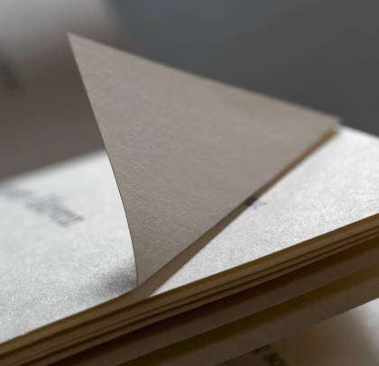 Photograph of a folded sheet of paper resting on a stack, the concept for the roof
